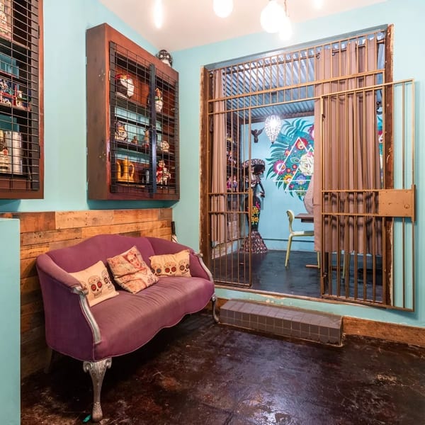 A vibrant waiting area with a purple sofa, turquoise walls, and a decorative metal gate leading to another room.
