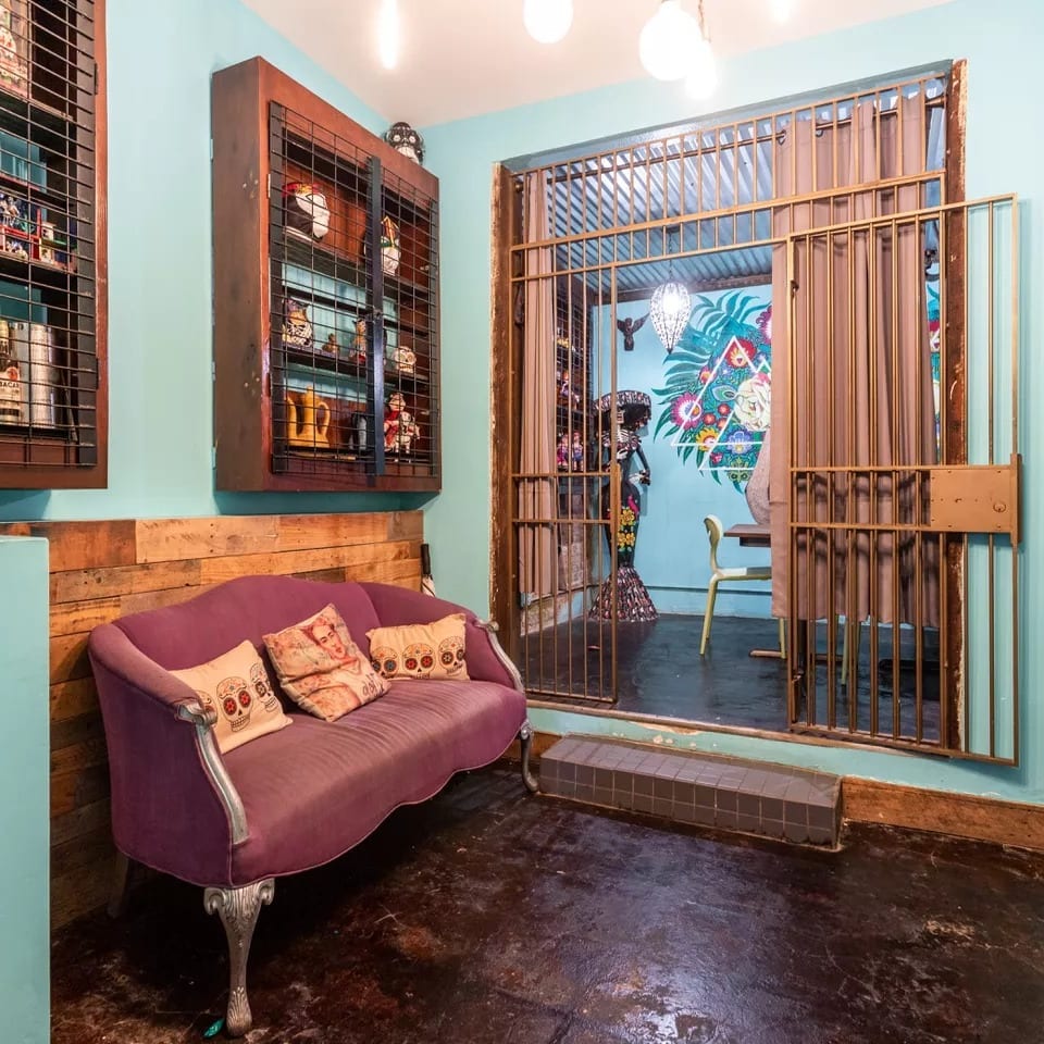 A vibrant waiting area with a purple sofa, turquoise walls, and a decorative metal gate leading to another room.